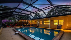 Ein Hallenbad mit Glasdach, umgeben von einer Poolanlage mit roten Stühlen und einem kleinen Tisch.