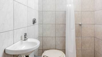 Un baño con lavamanos, inodoro y cortina de ducha blancos.