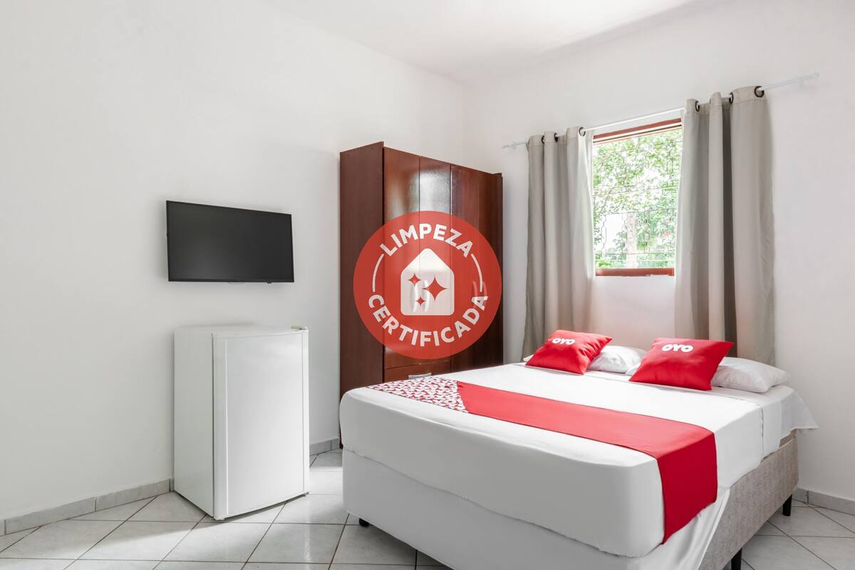 A hotel room with a bed, a wardrobe, a television, and a window with curtains.