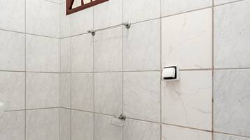 Un baño con inodoro, secamanos y ventana con marco marrón.