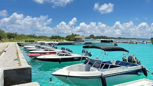 Un port de plaisance où sont amarrés plusieurs bateaux, un ciel bleu dégagé et une mer calme.