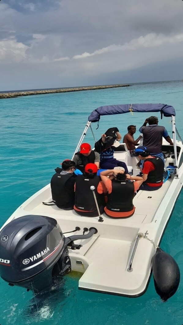 A small boat with several people on board, equipped with life jackets and a Yamaha outboard motor.