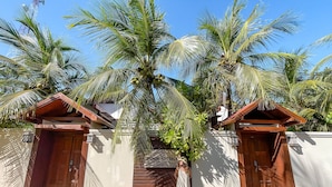 Une propriété située en bord de mer, comprenant deux cabanes en bois, un palmier et un panneau indiquant « Maison de plage ».