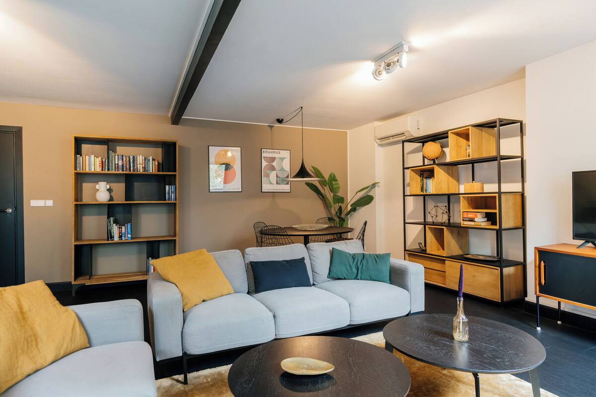 A modern living room with a grey sofa, a coffee table, and bookshelves.