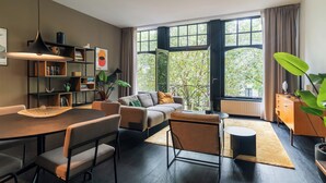 A modern living room with a dining area, large windows, and a view of greenery outside. - The Hunfeld (Utrecht)