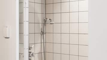 A shower with a handheld showerhead and a wall-mounted faucet, tiled walls, and a towel hanging on a rack.