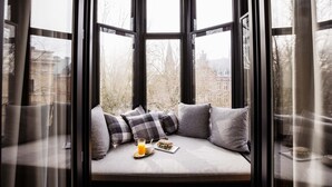 A bay window with a cushioned bench, a glass of orange juice, and a plate with food. - The Hunfeld (Utrecht)