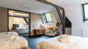 Ett hotellrum med två sängar, ett skrivbord, en stol, en TV och ett fönster.