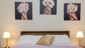 Ein Hotelzimmer mit einem Bett, zwei Nachttischlampen und drei an der Wand befestigten Bildern mit floralen Motiven.