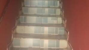 Una escalera con baldosas que alternan entre colores claros y oscuros que sube.