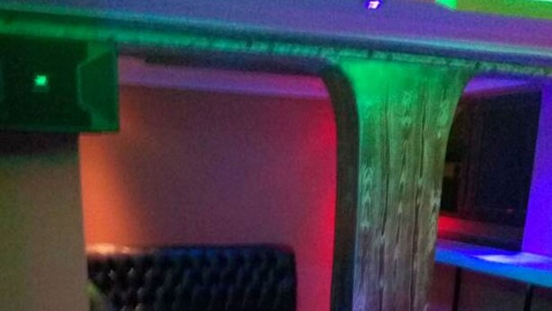 Una habitación tenuemente iluminada con piso a cuadros, un sofá de cuero negro y una pequeña mesa.
