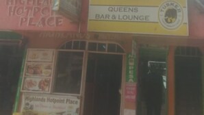 A building with multiple signs, including "Queens Bar & Lounge" and "Highlands Hotpoint Place".