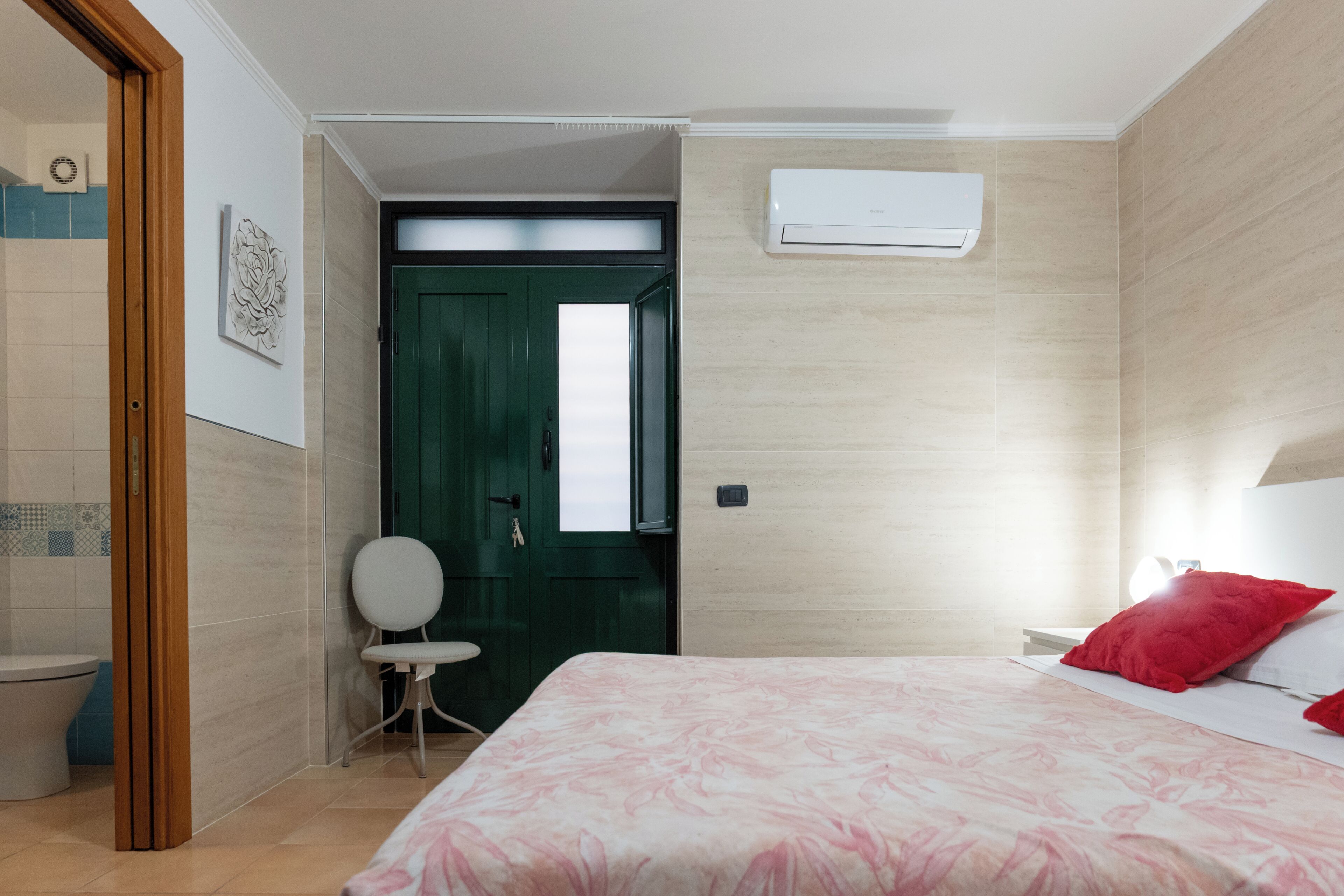 A hotel room with a bed, a chair, a toilet, and a door.