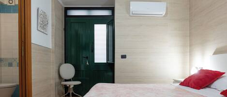 A hotel room with a bed, a chair, a toilet, and a door.