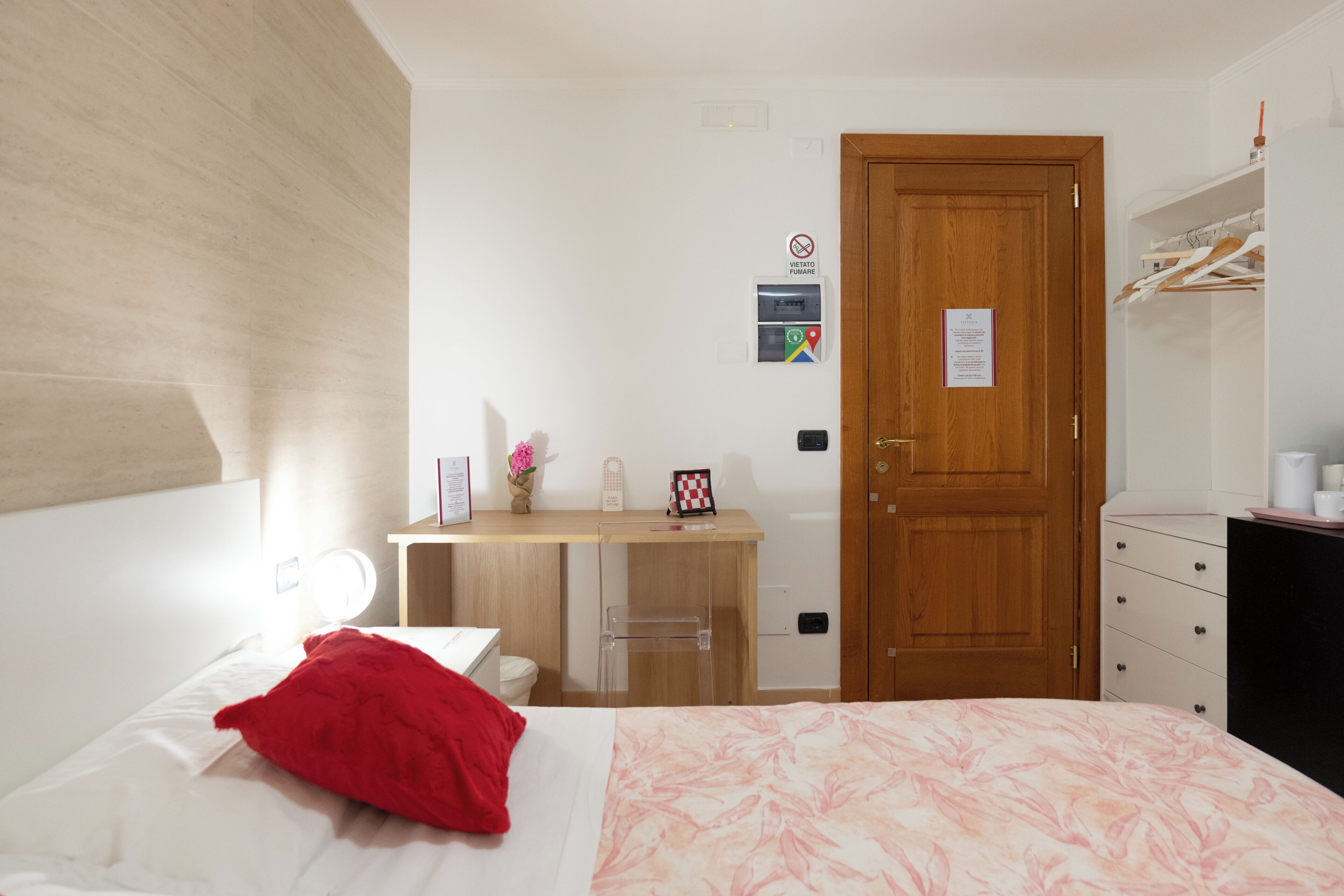 A hotel room with a bed, a desk, a wardrobe, and a door.