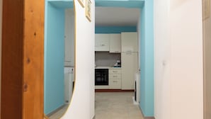Un pasillo estrecho que da a una cocina con armarios blancos y una pared azul de acento.