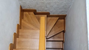 Una escalera de madera con barandilla y una pared texturizada en la parte superior.