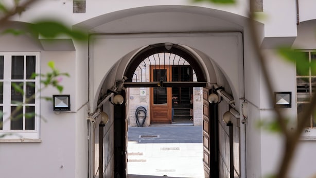 Entrada de un edificio con un arco de acceso, una puerta visible y un ventanal pequeño a la izquierda.