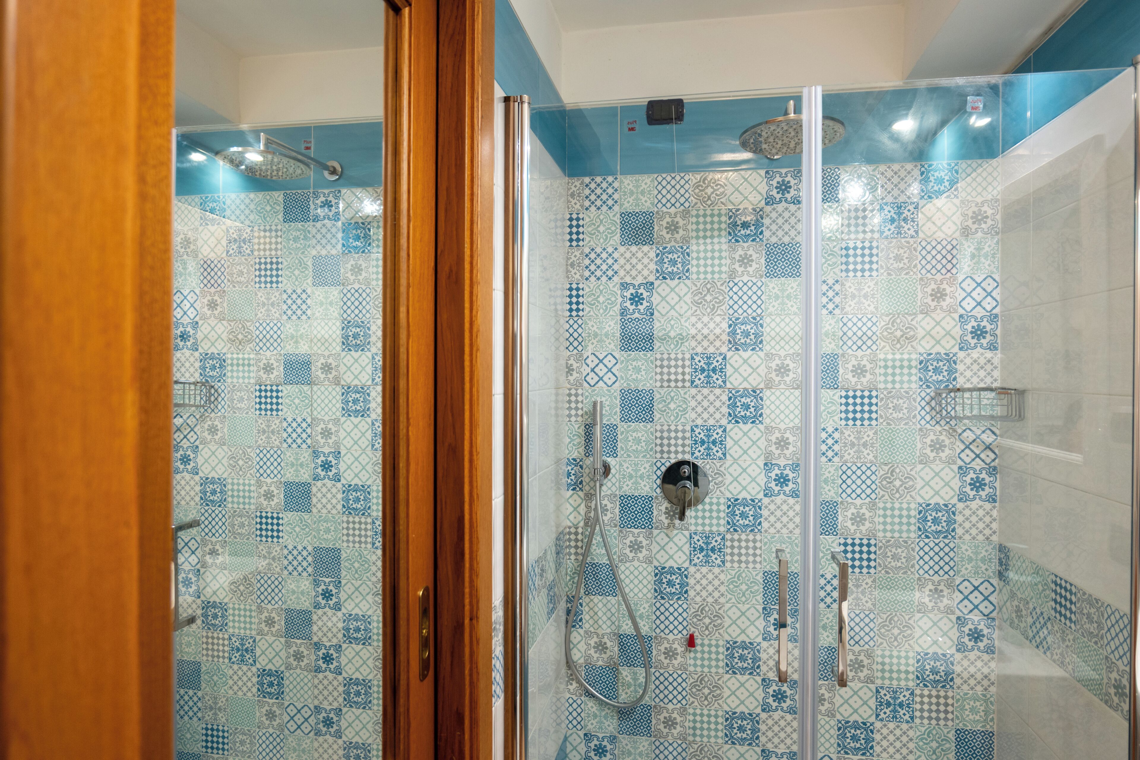 A shower area with a tiled wall and a glass door.
