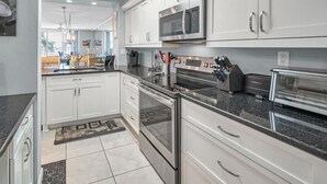 A modern kitchen with white cabinets, stainless steel appliances, and a granite countertop. - Waterfront 2BR/2BA condo in St. Petersburg with pool, hot tub, and beach access. (St. Petersburg)