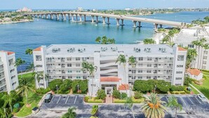 A multi-story hotel with a parking lot, located near a waterfront with a bridge in the background. - Waterfront 2BR/2BA condo in St. Petersburg with pool, hot tub, and beach access. (St. Petersburg)