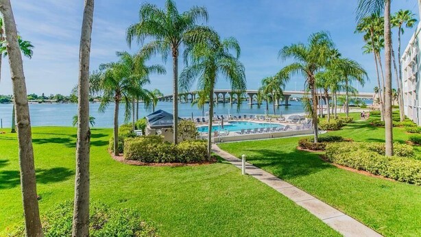 A resort with a swimming pool, palm trees, and a bridge in the background. - Waterfront 2BR/2BA condo in St. Petersburg with pool, hot tub, and beach access. (St. Petersburg)