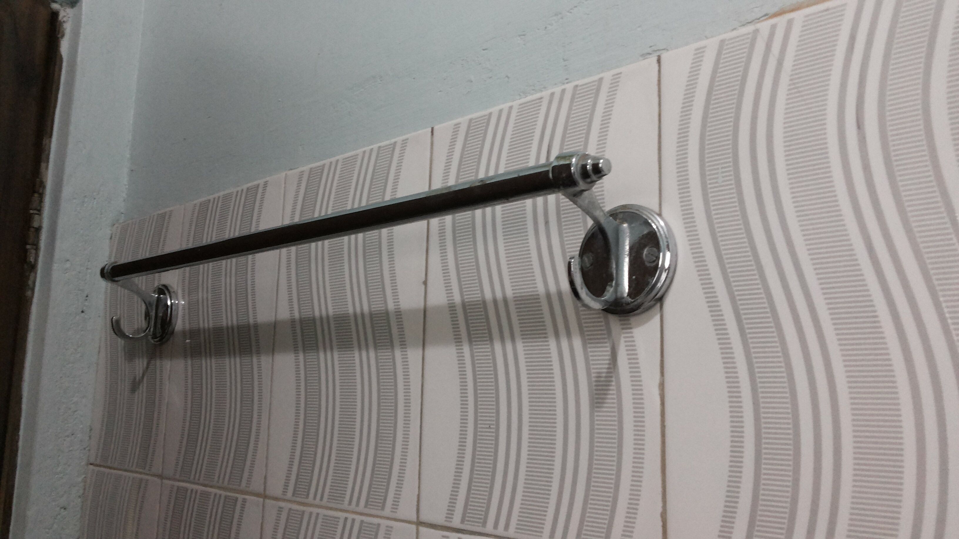 Une salle de bain avec un porte-serviettes fixé à un mur carrelé.