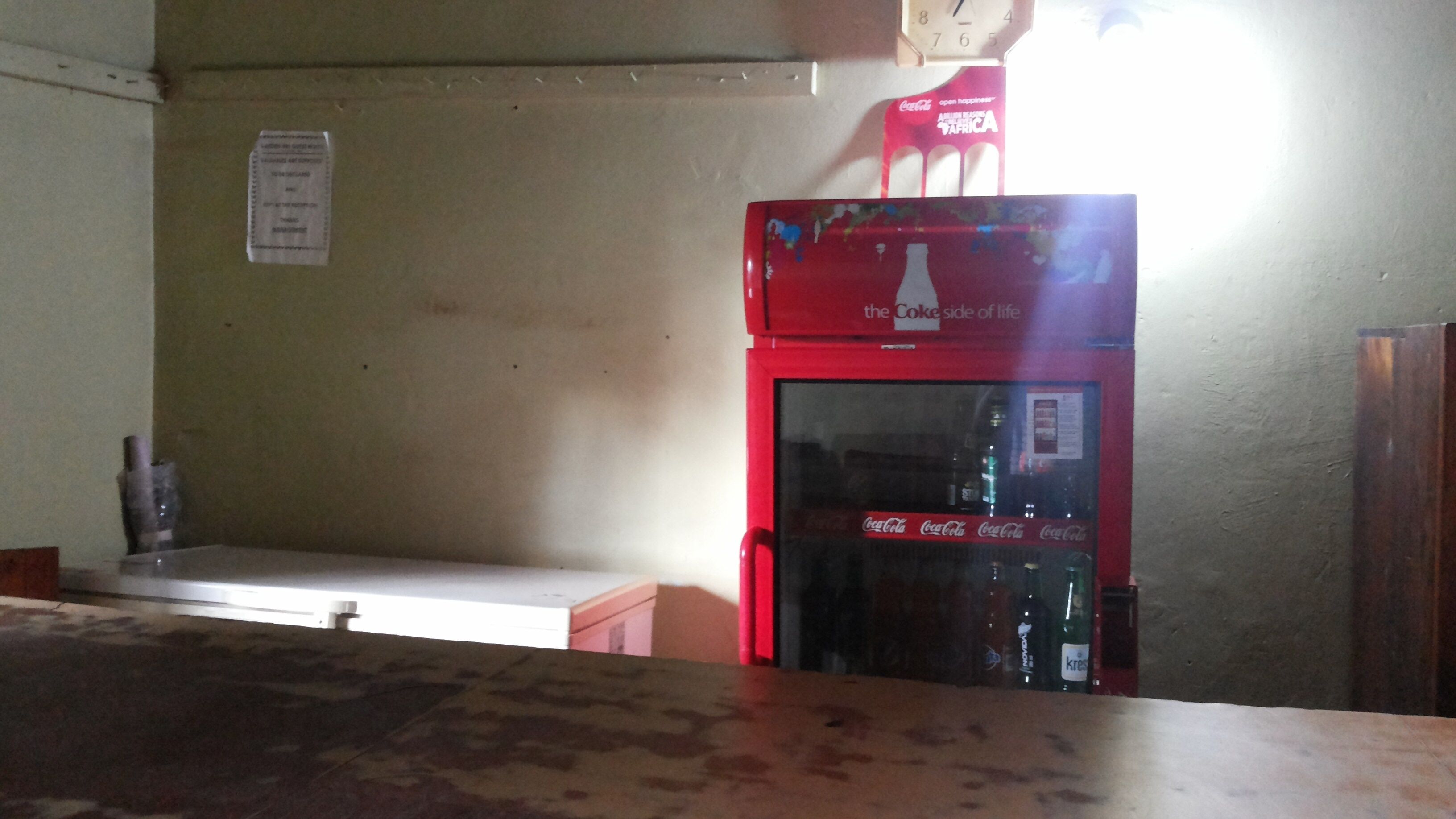 A room with a red refrigerator, a wooden table, and a wall-mounted sign.