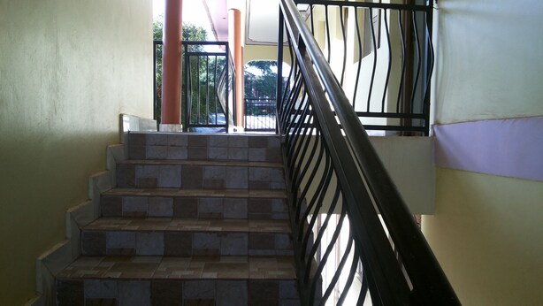 Un escalier avec des marches en pierre et une rampe en métal noir.