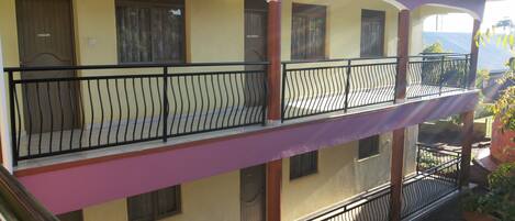 Un edificio de varios pisos con balcones, un toldo rojo y vistas a las montañas.