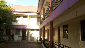 A courtyard with a building featuring a balcony and a staircase.