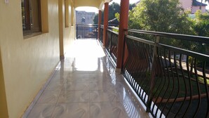 Un couloir au sol carrelé et un balcon doté d’une rambarde en métal.