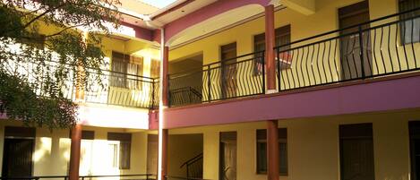 Un edificio de varios pisos con balcones, una escalera central y un patio.