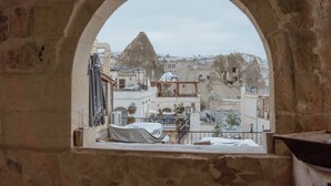 Vista através de uma janela em arco de um edifício com uma montanha coberta de neve ao fundo.