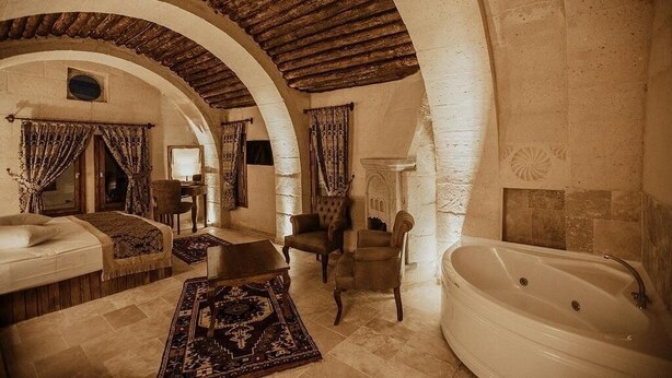 Quarto com teto abobadado, banheira, sofá e lareira.
