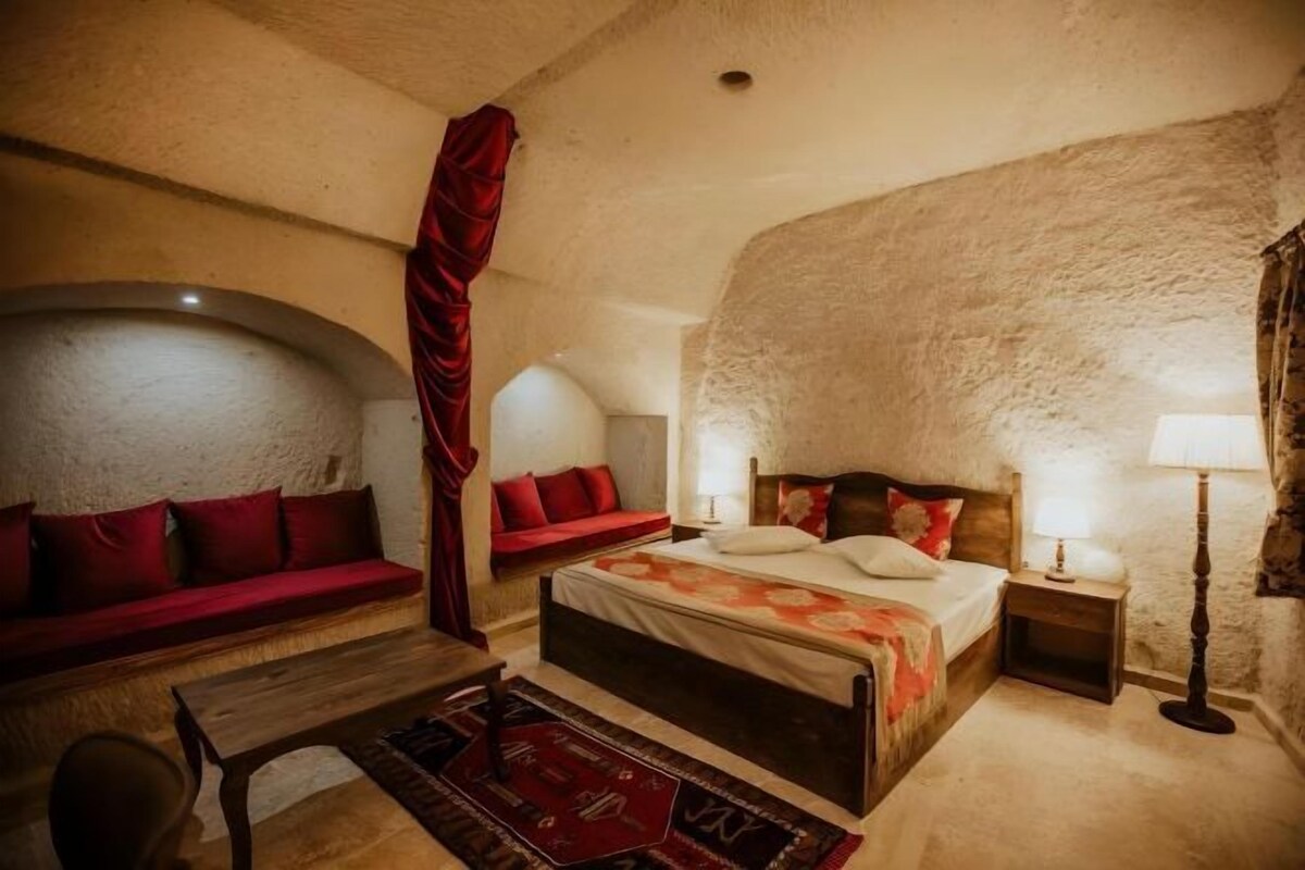 A bedroom with a large bed, a sofa, a chair, and a lamp.