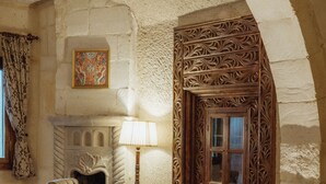 Quarto com lareira, duas poltronas, uma mesa e tapete estampado.