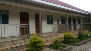 A building with a covered porch, stone steps, and metal railings. - Dubai Resort Hotel (Adjumani)