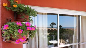 A balcony with a hanging flower pot and a view of the sea.