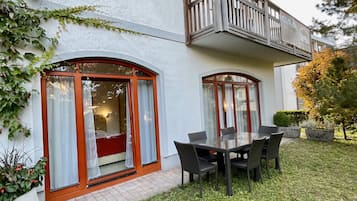 Een tweelaags huis met een balkon, een eethoek met buitenmeubilair en een verzorgd gazon.
