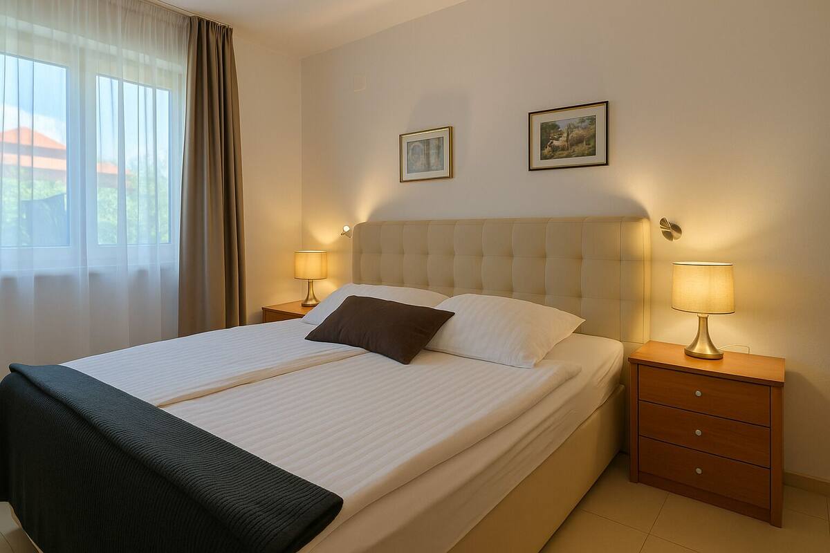 A neatly made bed with a white and brown pillow, two bedside lamps, and a small wooden nightstand.