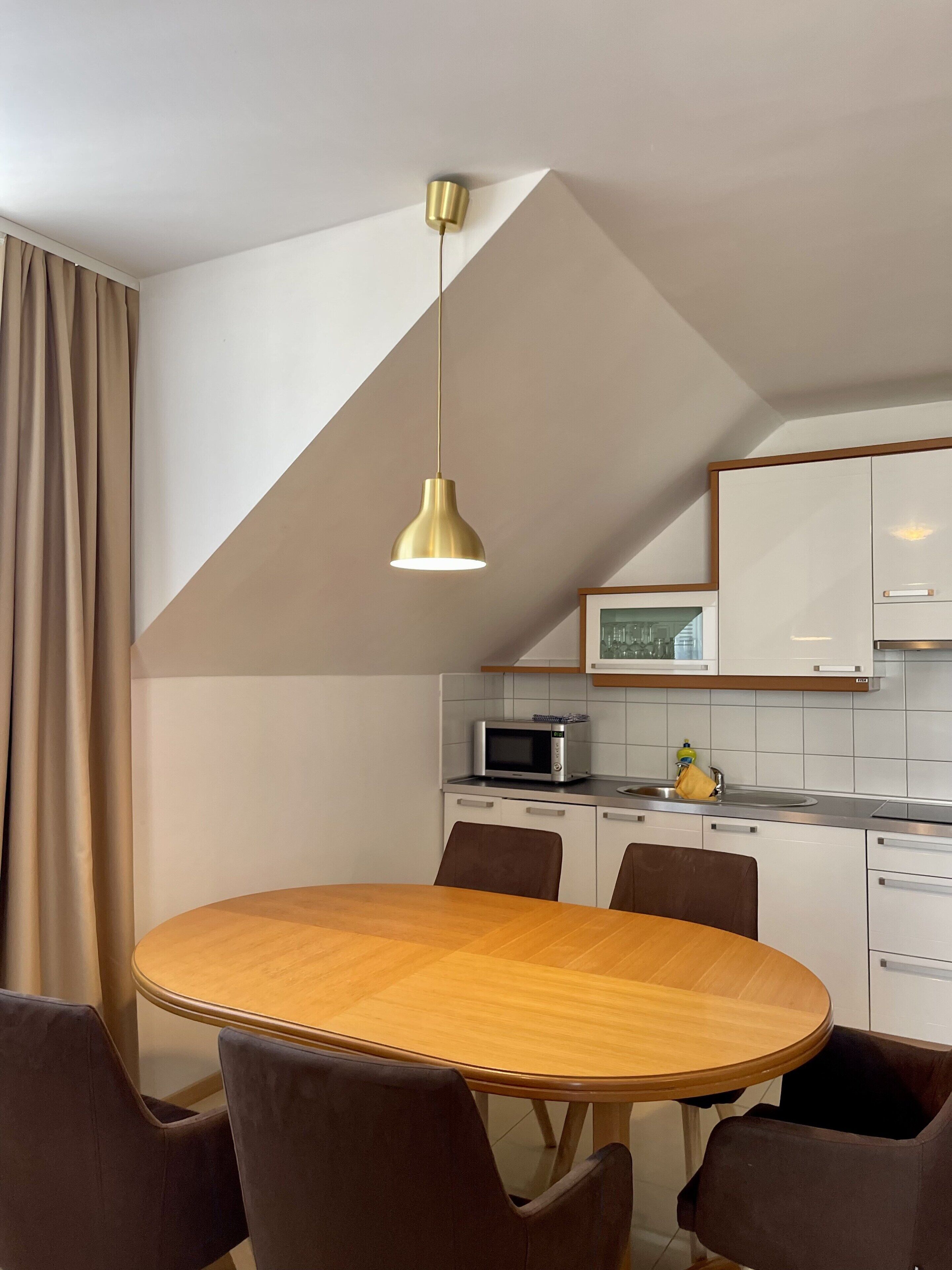 Una cocina moderna con una mesa redonda de madera y seis sillas, un microondas y un fregadero.