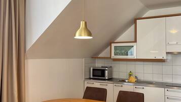 Una cocina moderna con una mesa redonda de madera y seis sillas, un microondas y un fregadero.
