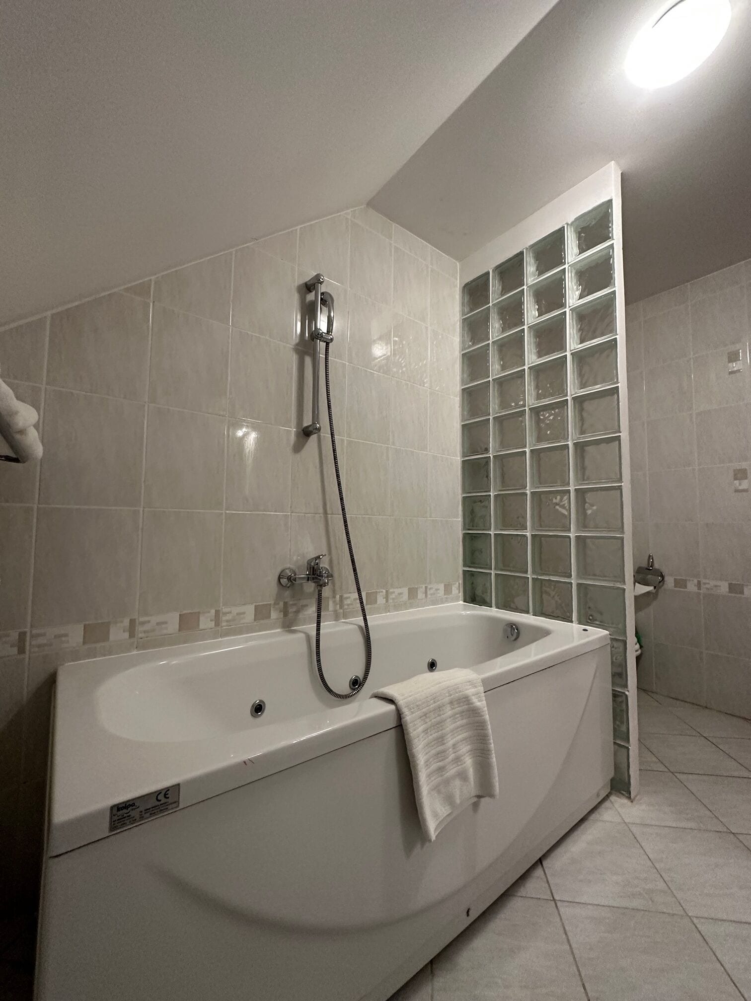 A modern bathroom with a large bathtub, a glass shower enclosure, and tiled walls.