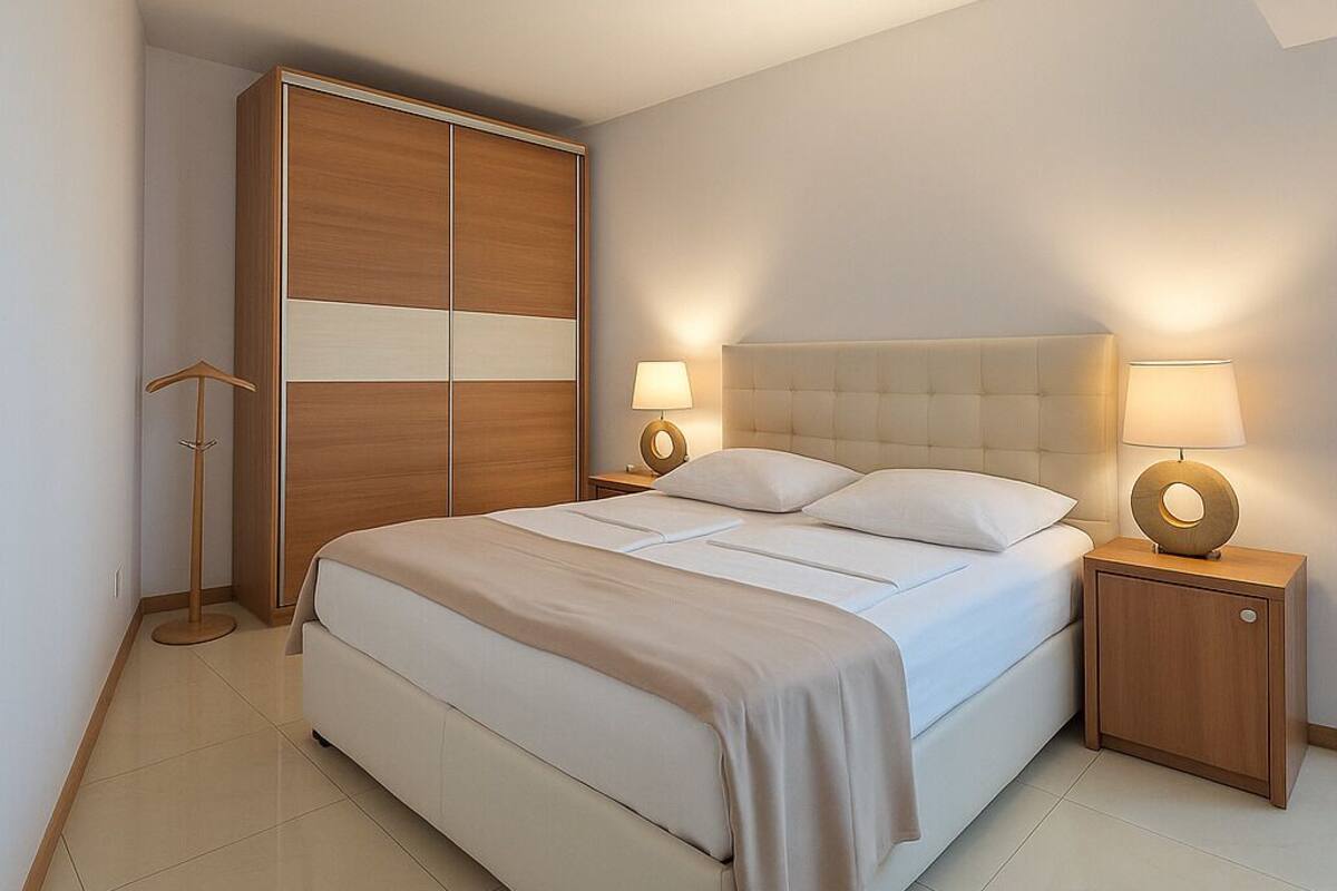 A modern bedroom with a large bed, a wardrobe, and two bedside tables with lamps.