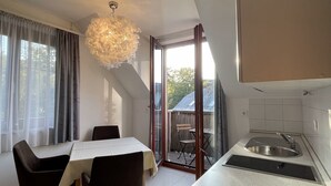 Una cocina moderna con pileta integrada, una zona de comedor con mesa y sillas, y un ventanal con cortinas.