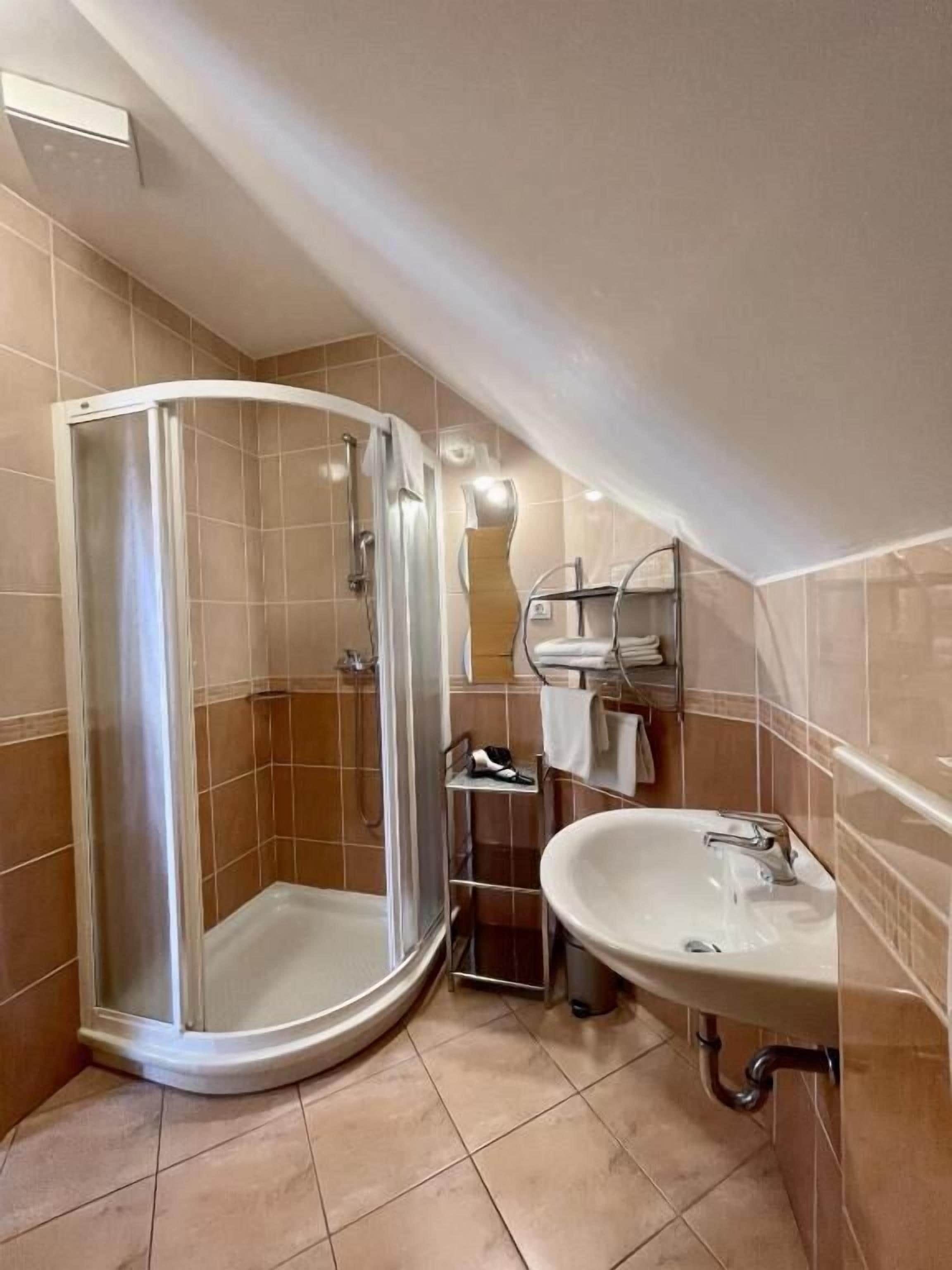 A bathroom with a glass-enclosed shower, a sink, and a towel rack.