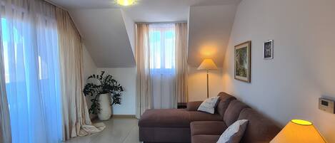 Een moderne woonkamer met een bruine modulaire bank, een staande lamp en een potplant.
