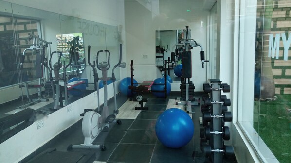 A gym with exercise equipment, large mirrors, and exercise balls. - Hard Break Hotel and Suite (Enugu)