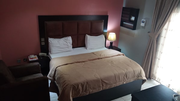 A hotel room with a bed, bedside tables, a lamp, and a window with curtains. - Hard Break Hotel and Suite (Enugu)